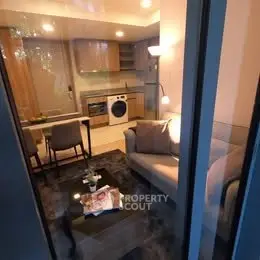 Modern living room with integrated kitchen and washing machine, cozy seating area, and stylish decor.