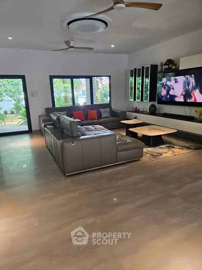 Spacious modern living room with large sectional sofa and garden view, perfect for relaxation and entertainment.