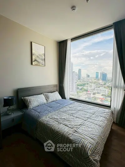 Modern bedroom with large window offering stunning city view, featuring cozy bed and stylish decor.