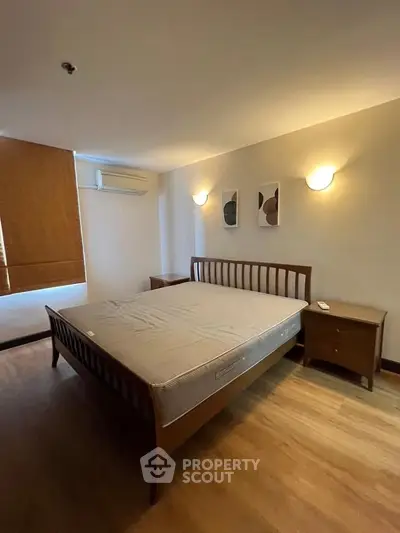 Spacious bedroom with wooden flooring and modern decor in a cozy apartment.