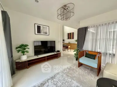 Modern living room with stylish decor, large TV, and elegant lighting in a bright, open space.
