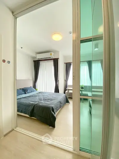 Modern bedroom with glass sliding doors and natural light in a stylish apartment.