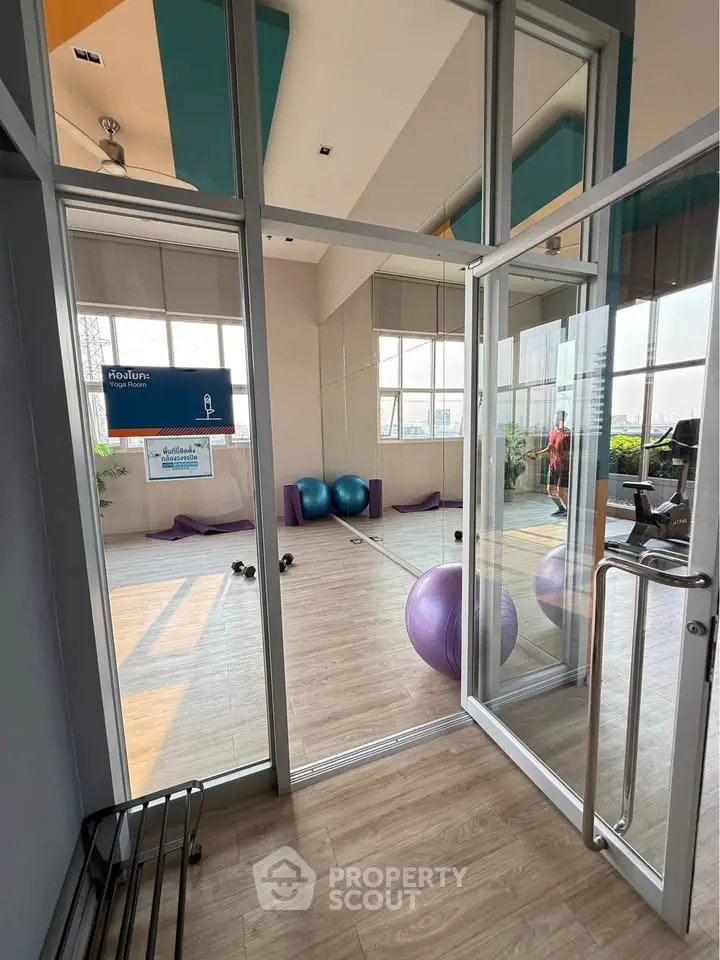 Modern gym with exercise balls and weights in a bright, glass-walled room.