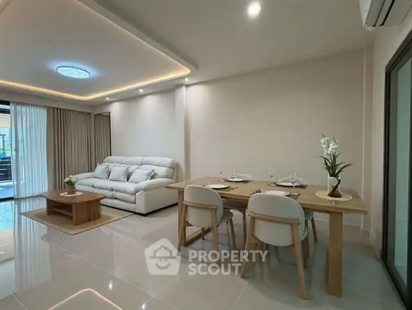 Modern living room with elegant dining area and cozy sofa, featuring sleek lighting and stylish decor.