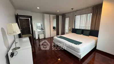 Spacious bedroom with elegant hardwood floors and modern furnishings in a high-rise apartment.