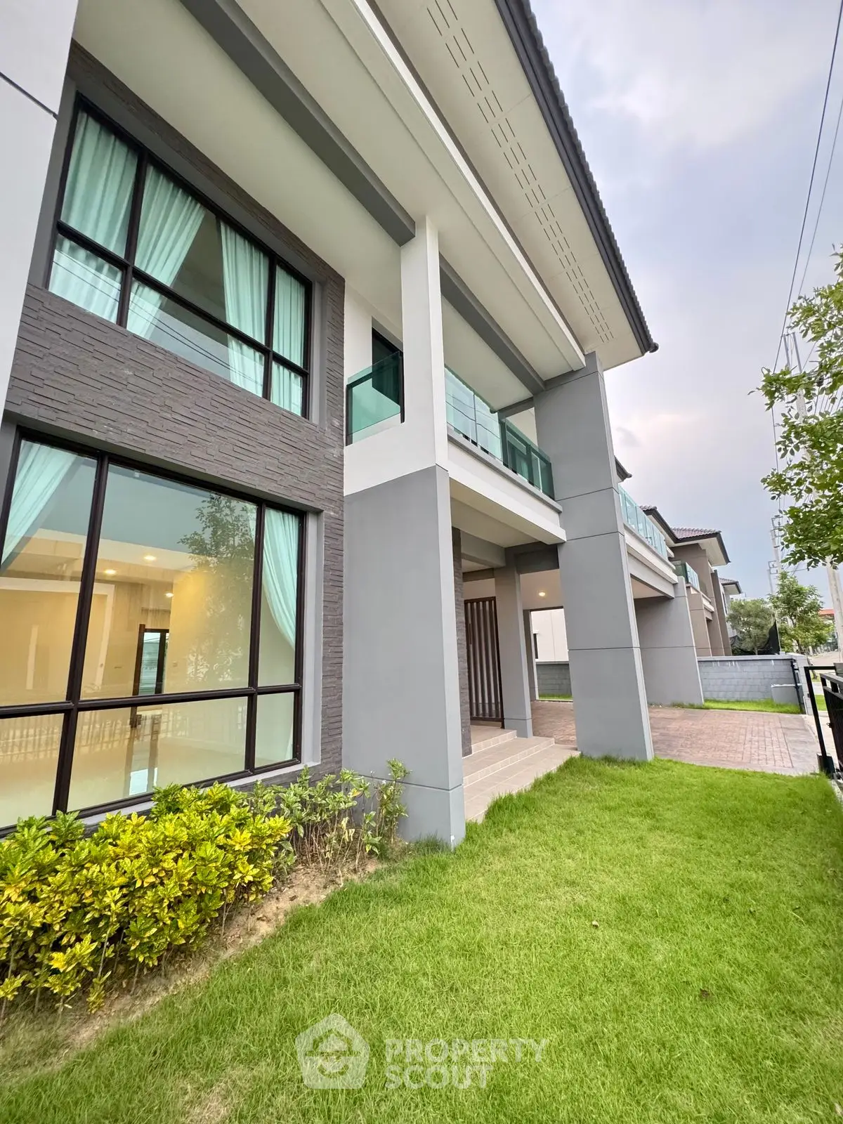 Modern two-story house with large windows and lush green lawn