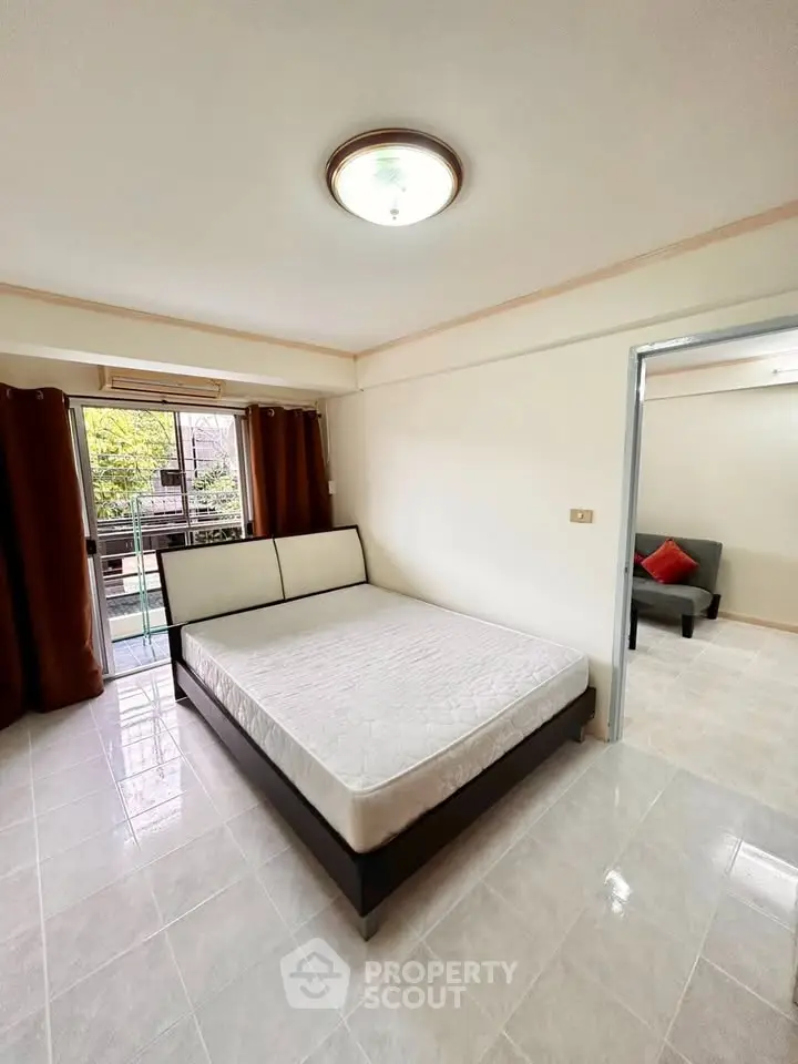 Spacious bedroom with large window and balcony access in modern apartment.