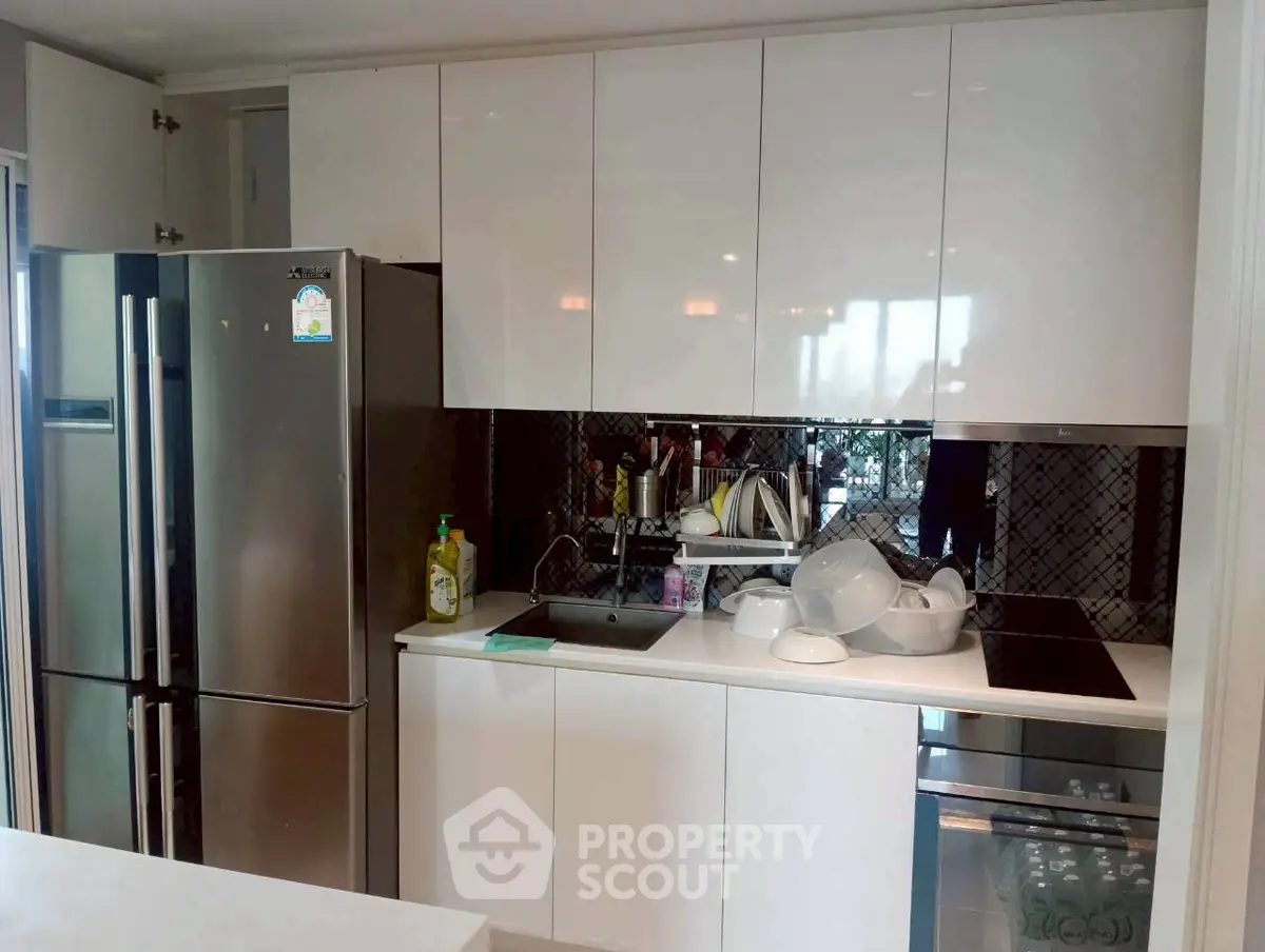 Modern kitchen with sleek cabinets, stainless steel fridge, and built-in oven in a stylish apartment.