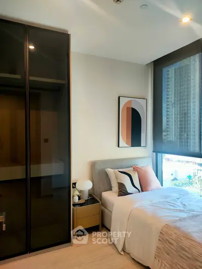 Modern bedroom with large window and stylish decor in urban apartment.