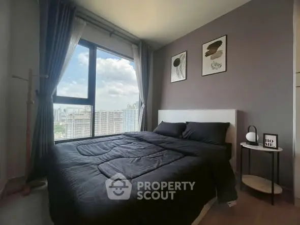 Modern bedroom with large window offering stunning city view, stylish decor, and cozy ambiance.