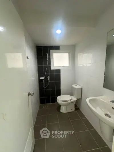 Modern bathroom with sleek design, featuring a shower, toilet, and sink in a compact layout.