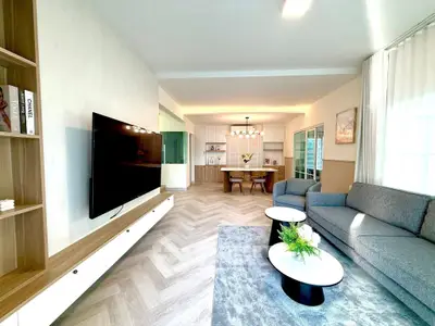 Modern open-plan living room with stylish furniture and large TV, perfect for contemporary living.