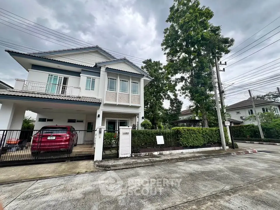 Charming two-story house with lush greenery and spacious driveway in a serene neighborhood.