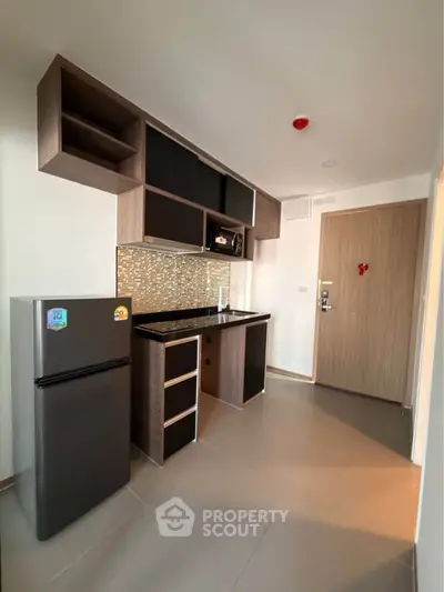 Modern kitchen with sleek cabinetry and compact fridge in a stylish apartment.