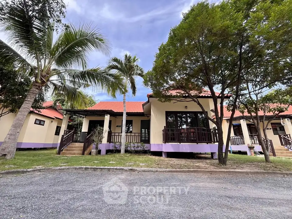 Charming tropical villa with red roof and lush greenery, perfect for serene living.