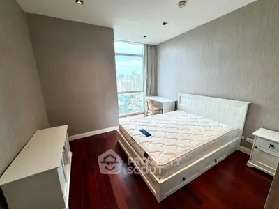 Spacious bedroom with city view, featuring elegant wooden flooring and modern white furniture.