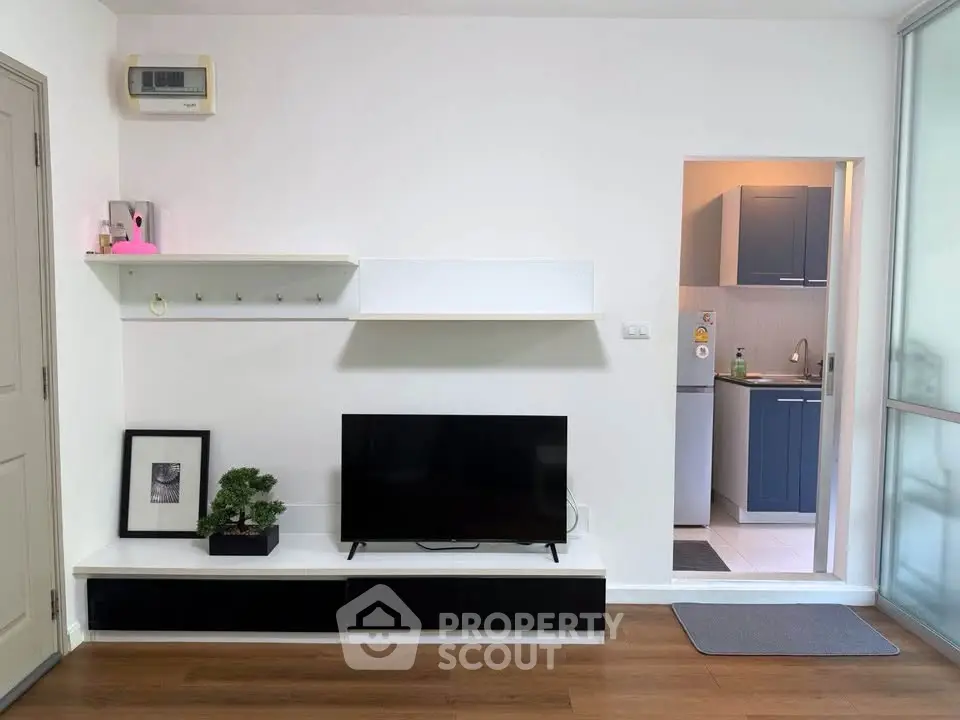 Modern living room with sleek TV setup and view into stylish kitchen