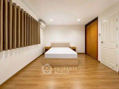 Spacious minimalist bedroom with wooden flooring and modern design.