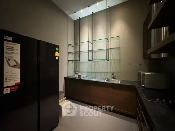 Modern kitchen with sleek design, featuring a black refrigerator, built-in shelves, and stainless steel appliances.