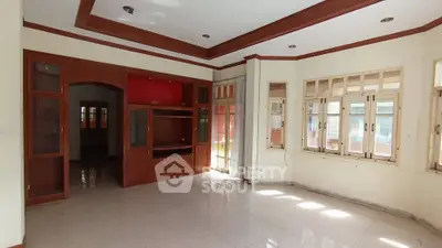 Spacious living room with built-in wooden cabinets and large windows