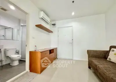 Modern living room with air conditioning and bathroom access, featuring sleek furniture and neutral tones.
