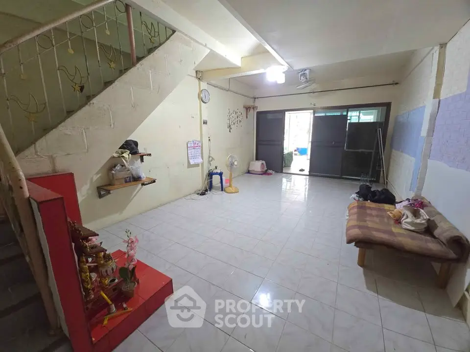 Spacious living room with tiled floor and staircase, ideal for family gatherings.