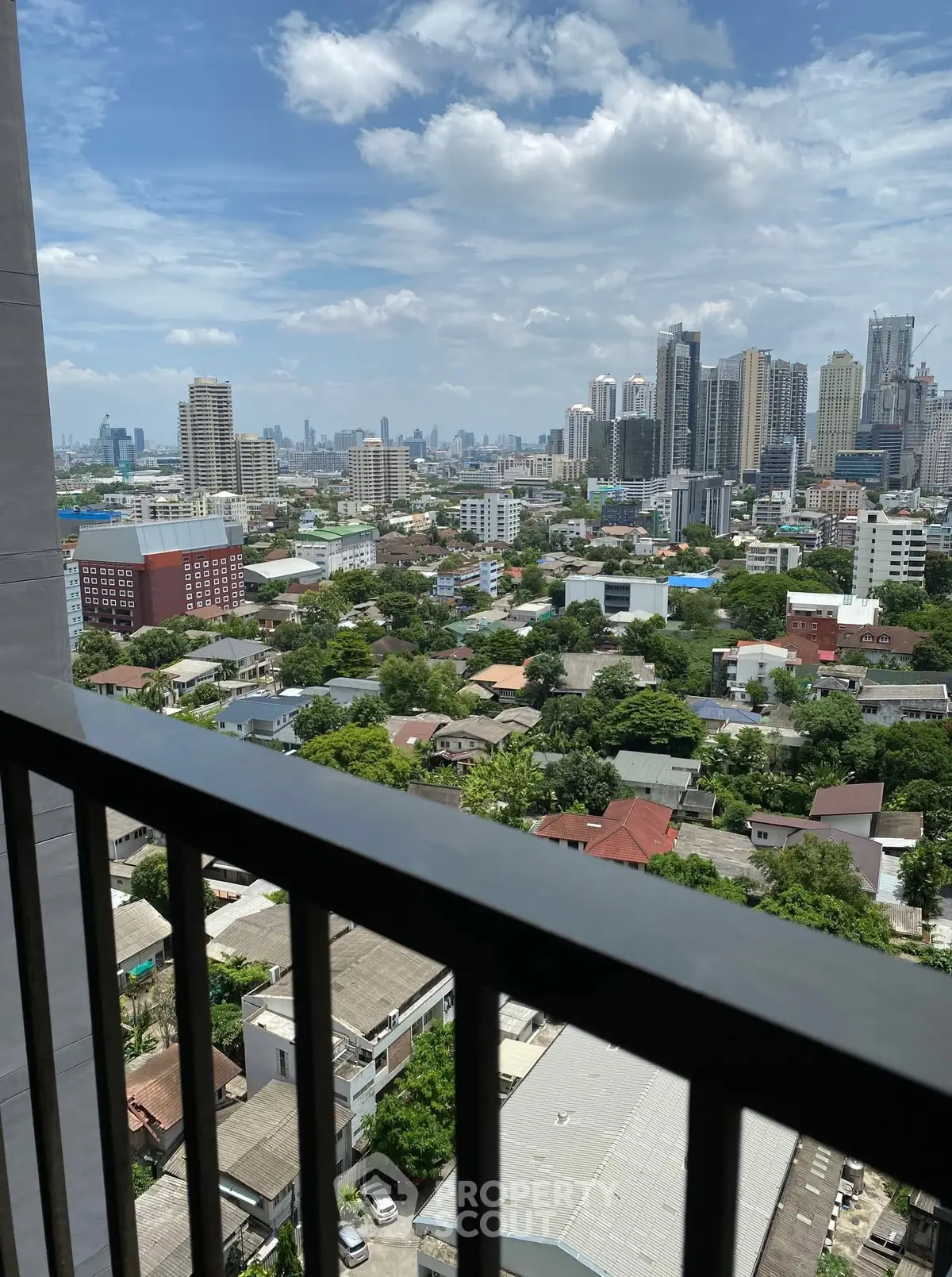 Stunning cityscape view from a high-rise balcony showcasing urban skyline and lush greenery.
