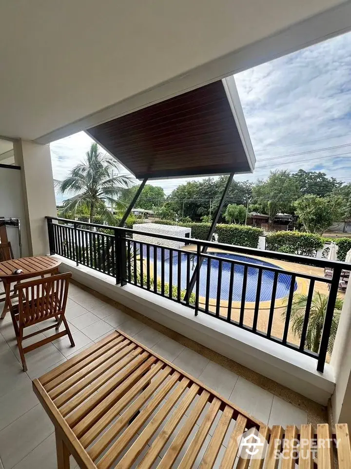 Spacious balcony with pool view and wooden furniture in tropical setting