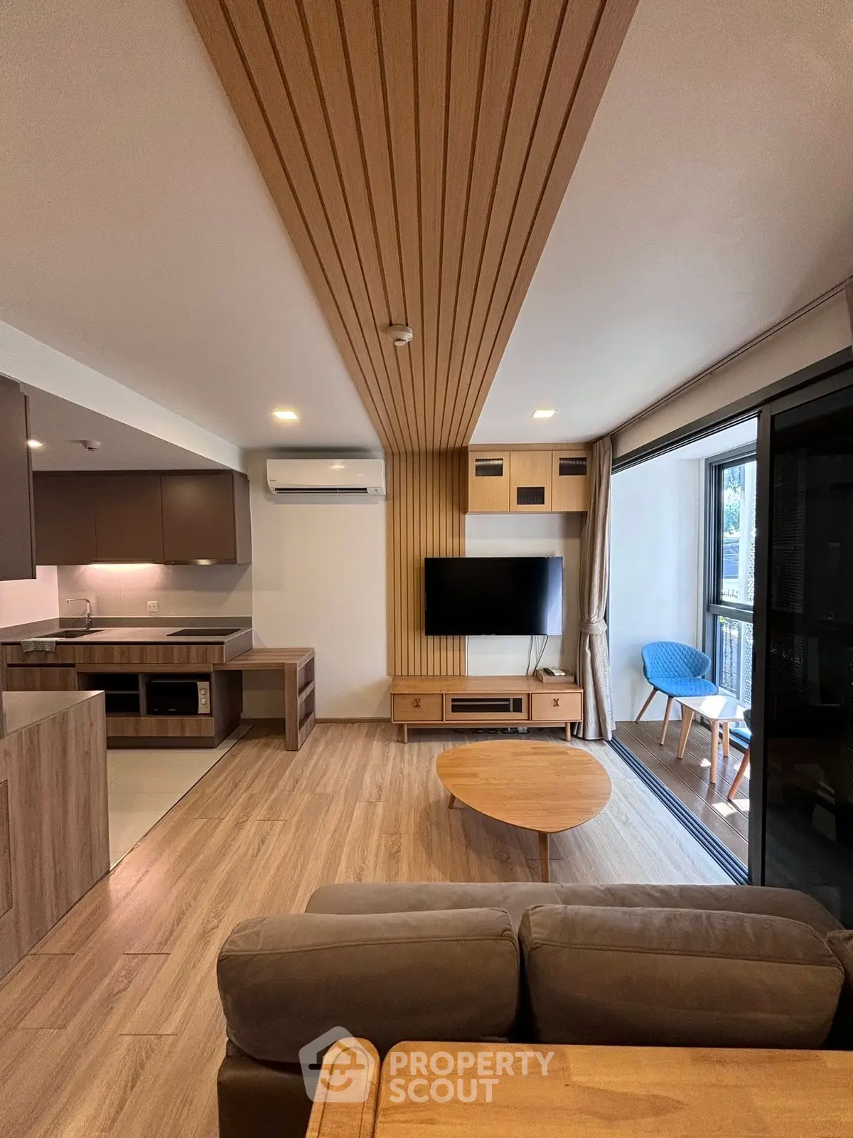 Modern living room with open kitchen and balcony, featuring stylish wood paneling and contemporary furniture.