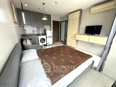 Modern studio apartment with integrated kitchen and cozy sleeping area, featuring a washing machine and TV.