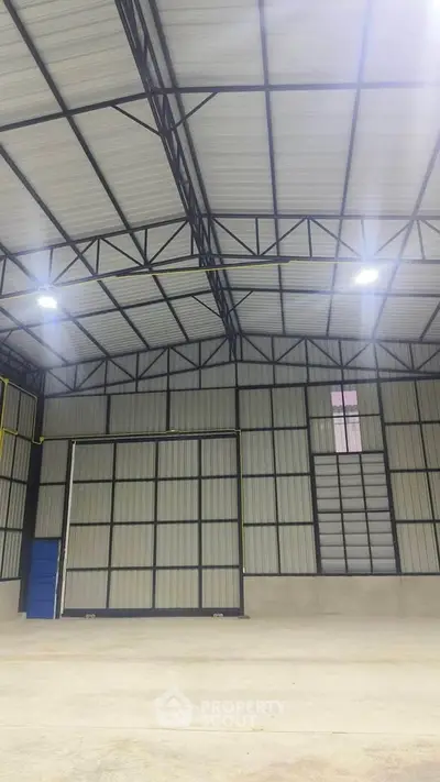 Spacious industrial warehouse with high ceilings and metal framework, ideal for storage or manufacturing.