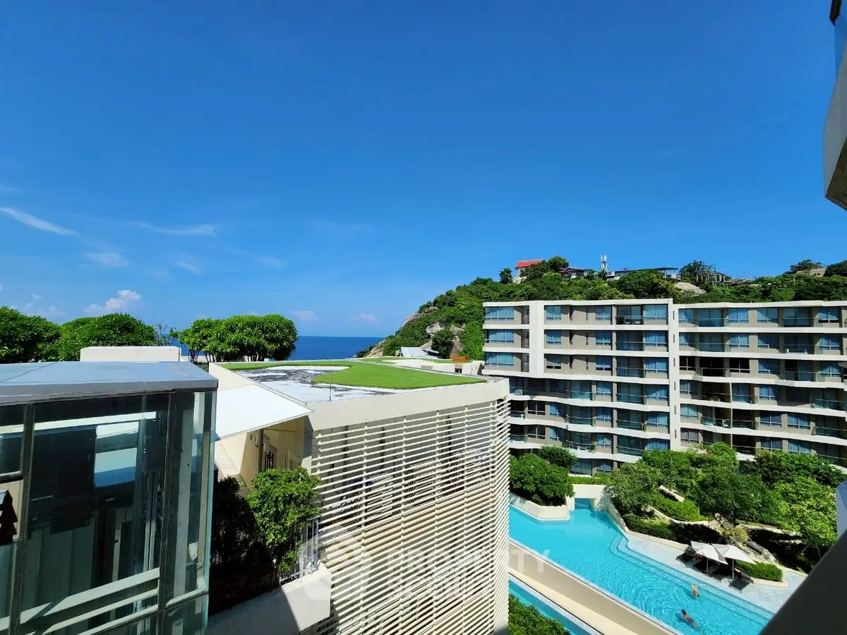 Stunning ocean view from modern apartment complex with pool and lush greenery.