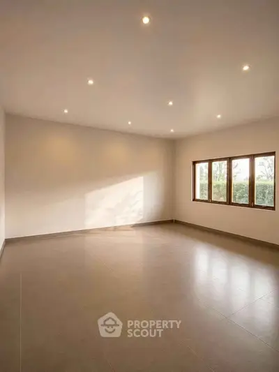 Spacious empty room with large windows and recessed lighting, perfect for customization.