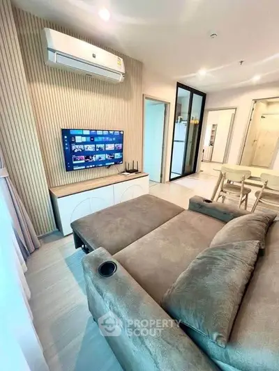 Modern living room with stylish sofa, wall-mounted TV, and air conditioning in a cozy apartment.