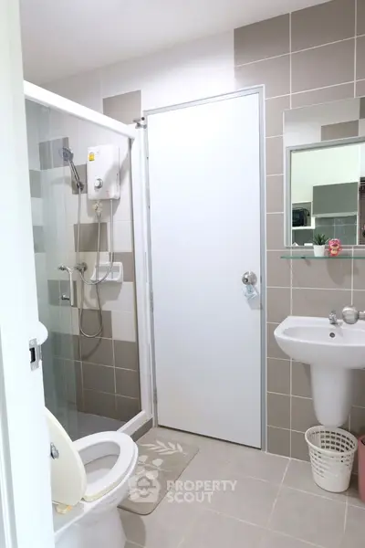 Modern bathroom with shower, toilet, and sink in a stylish tiled design.