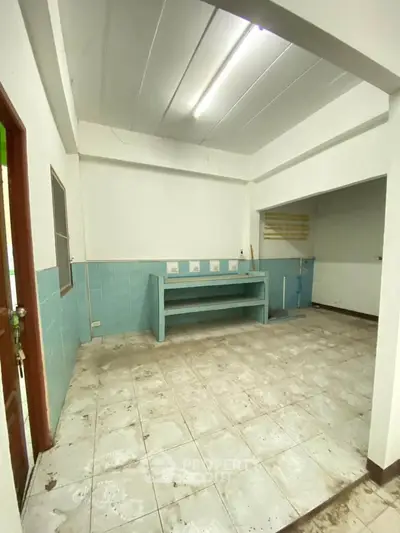 Spacious kitchen area with tiled flooring and ample counter space in a real estate property.