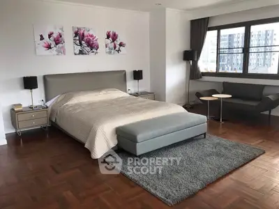 Spacious bedroom with modern decor and large window view in luxury apartment.