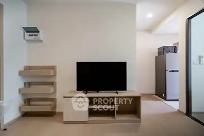 Modern living room with sleek TV stand and adjacent kitchen area in a stylish apartment.