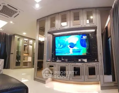 Luxurious living room with elegant cabinetry and large TV, perfect for entertainment and relaxation.