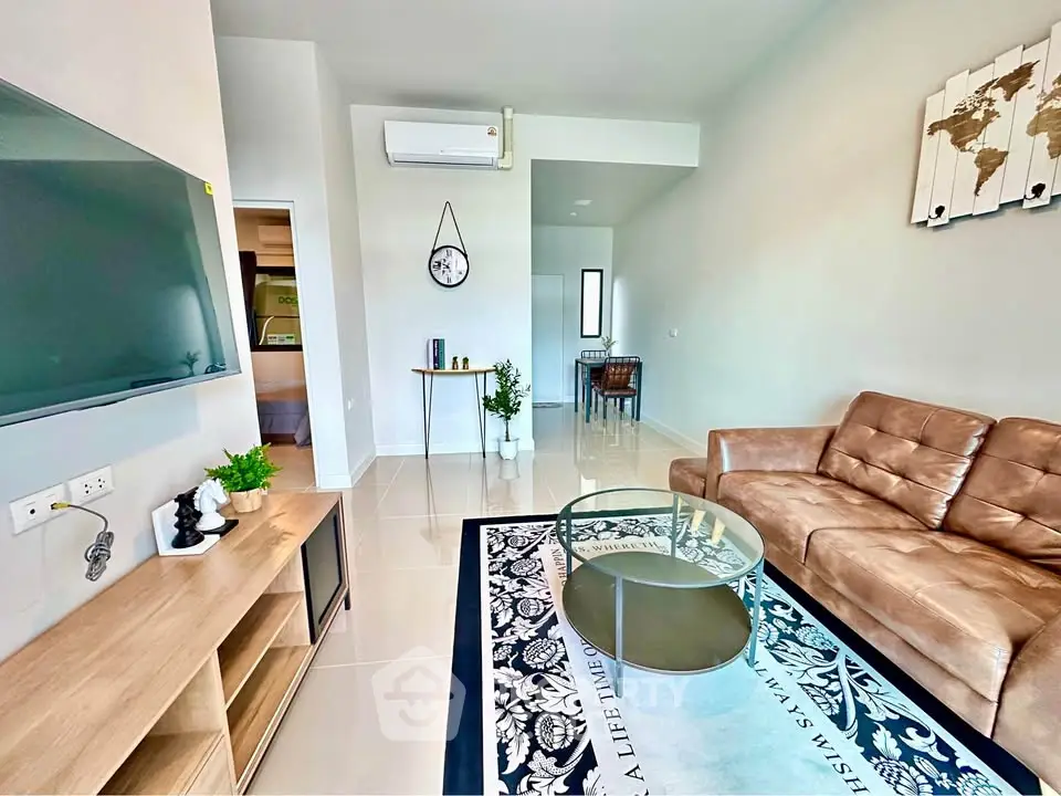 Modern living room with sleek furniture and wall art, featuring a cozy brown sofa and glass coffee table.