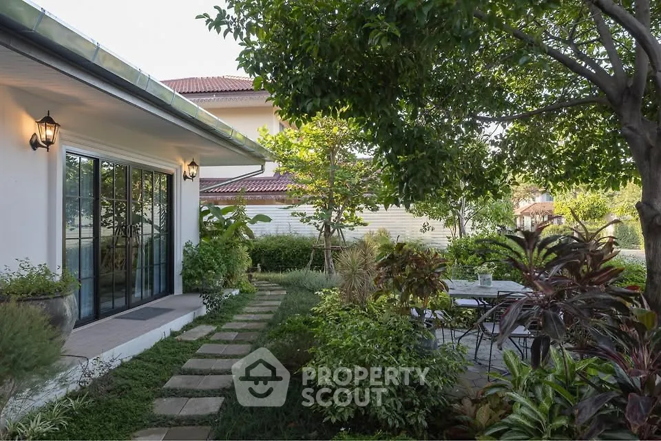 Charming garden view of a modern home with lush greenery and outdoor seating area.
