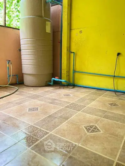 Spacious utility area with water tank and tiled flooring, ideal for storage or laundry setup.