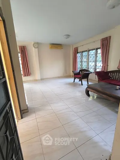 Spacious living room with tiled flooring and large windows for natural light.