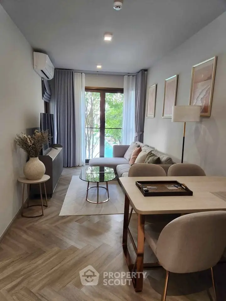 Modern living room with stylish decor, cozy seating, and large window offering natural light and greenery view.