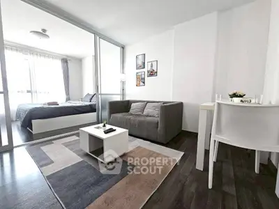 Modern studio apartment with cozy living area and bedroom, featuring sleek furniture and natural light.