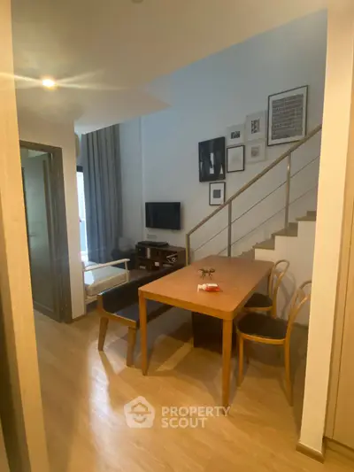 Modern living room with stylish decor and wooden dining table, perfect for cozy gatherings.