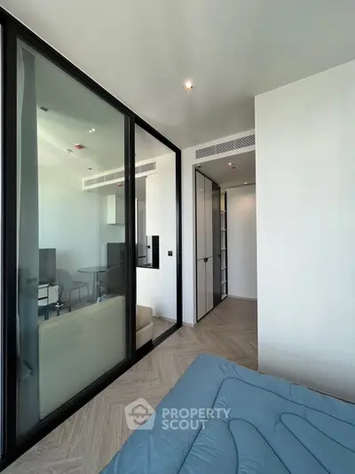 Modern bedroom with glass partition and sleek design in a contemporary apartment.