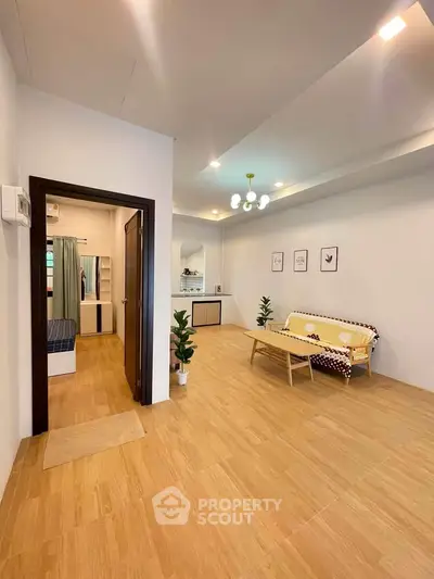 Spacious living room with modern decor and wooden flooring, featuring a cozy sofa and stylish lighting.