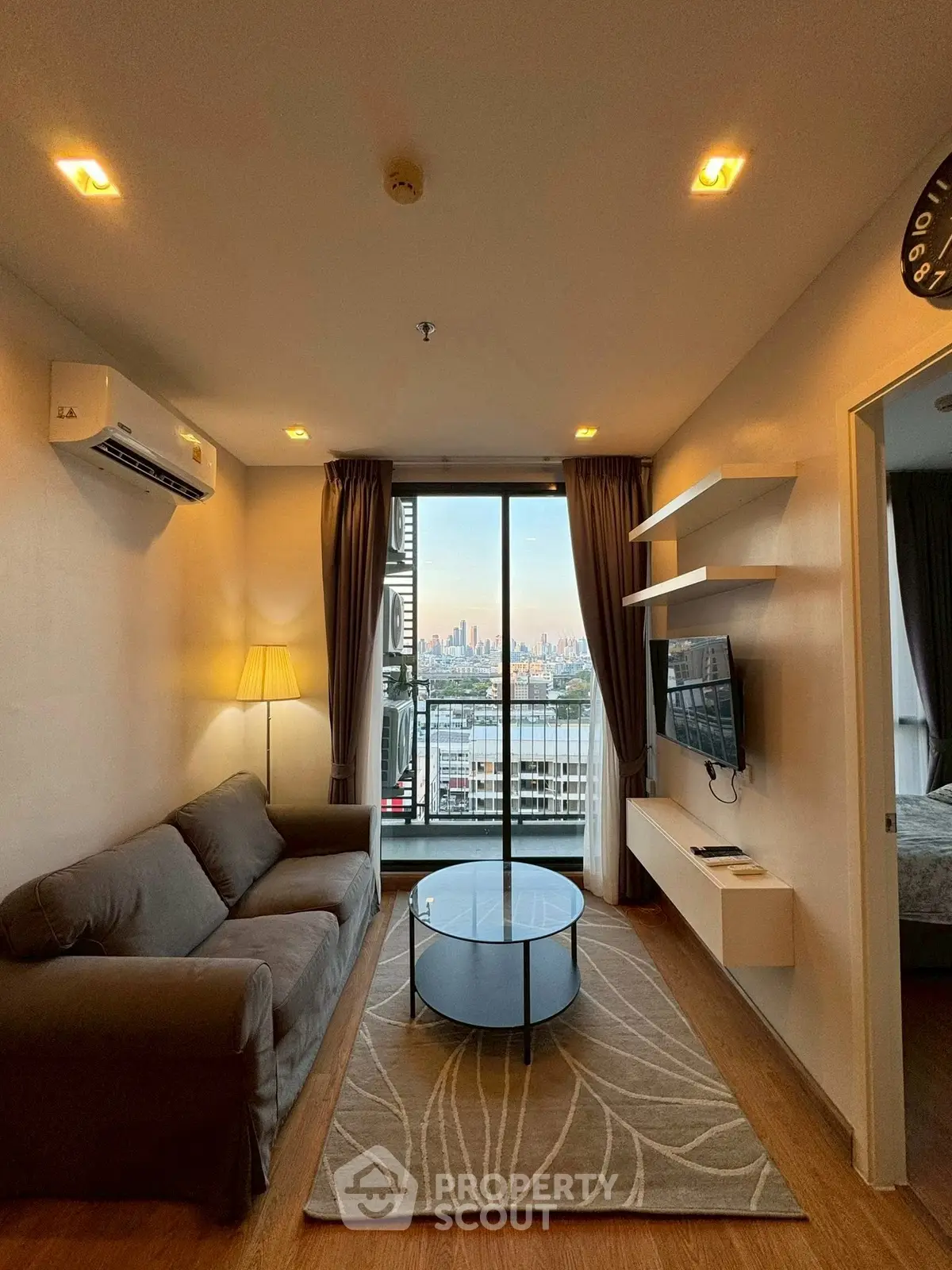 Modern living room with city view, cozy sofa, and wall-mounted TV in a stylish apartment.