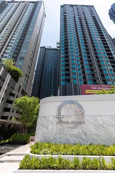 Modern high-rise residential building with sleek design and lush landscaping at Life Asoke Rama 9.